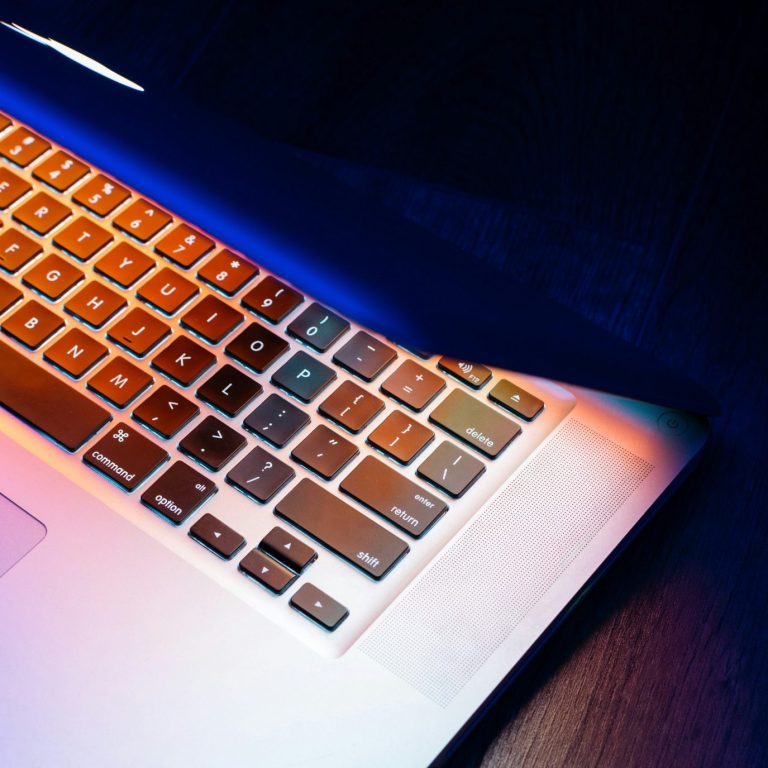 Das Bild zeigt eine teilweise geschlossene Laptop-Tastatur mit farbiger Beleuchtung.