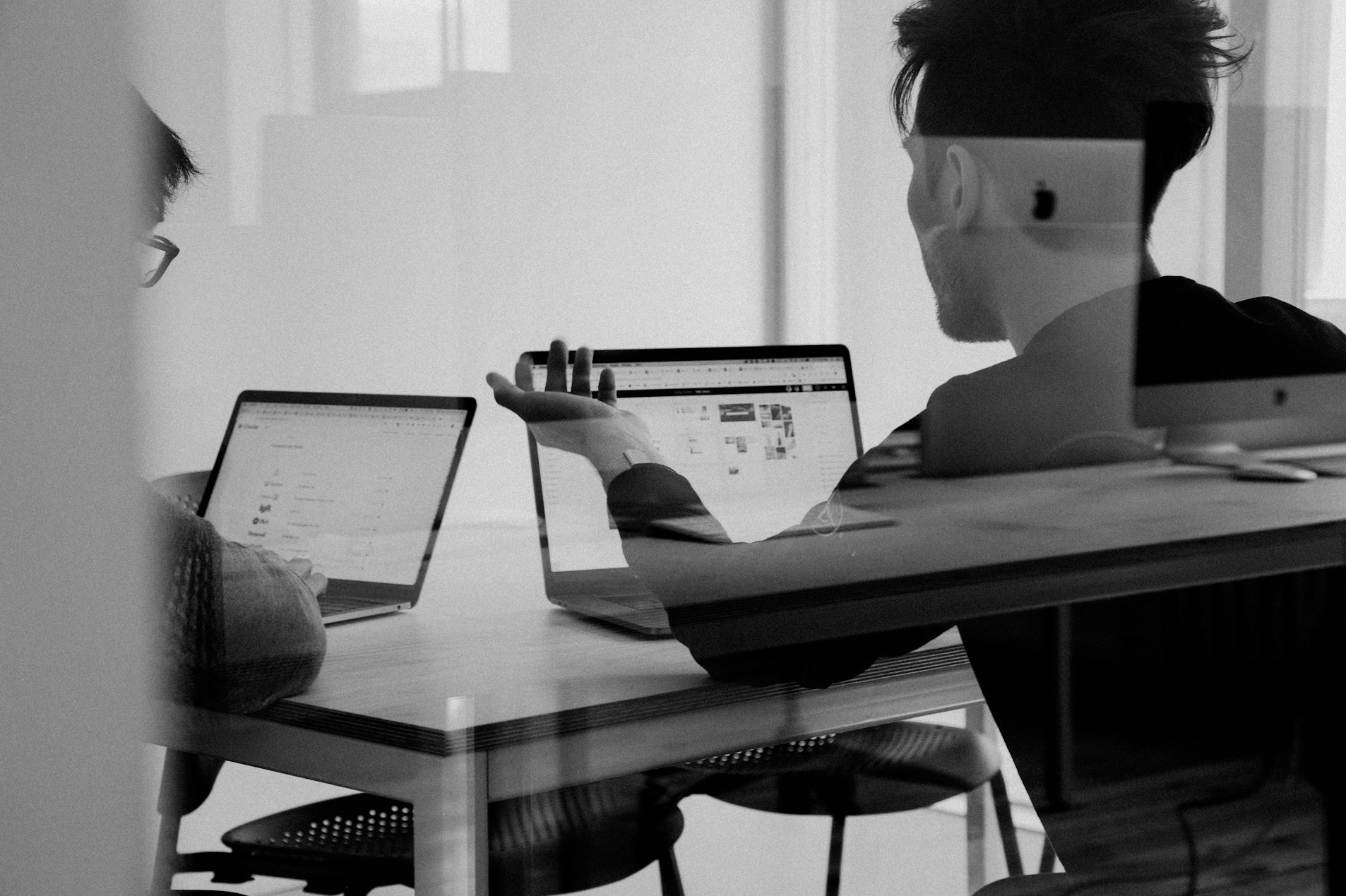 Zwei Personen an Laptops, tintenfarbenes Licht, fokussiert auf eine Bildschirmpräsentation.