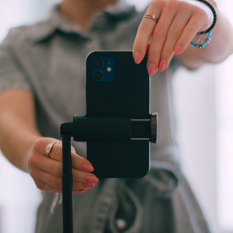 Eine Person hält ein Smartphone in der Hand, während sie auf sich selbst fokussiert.